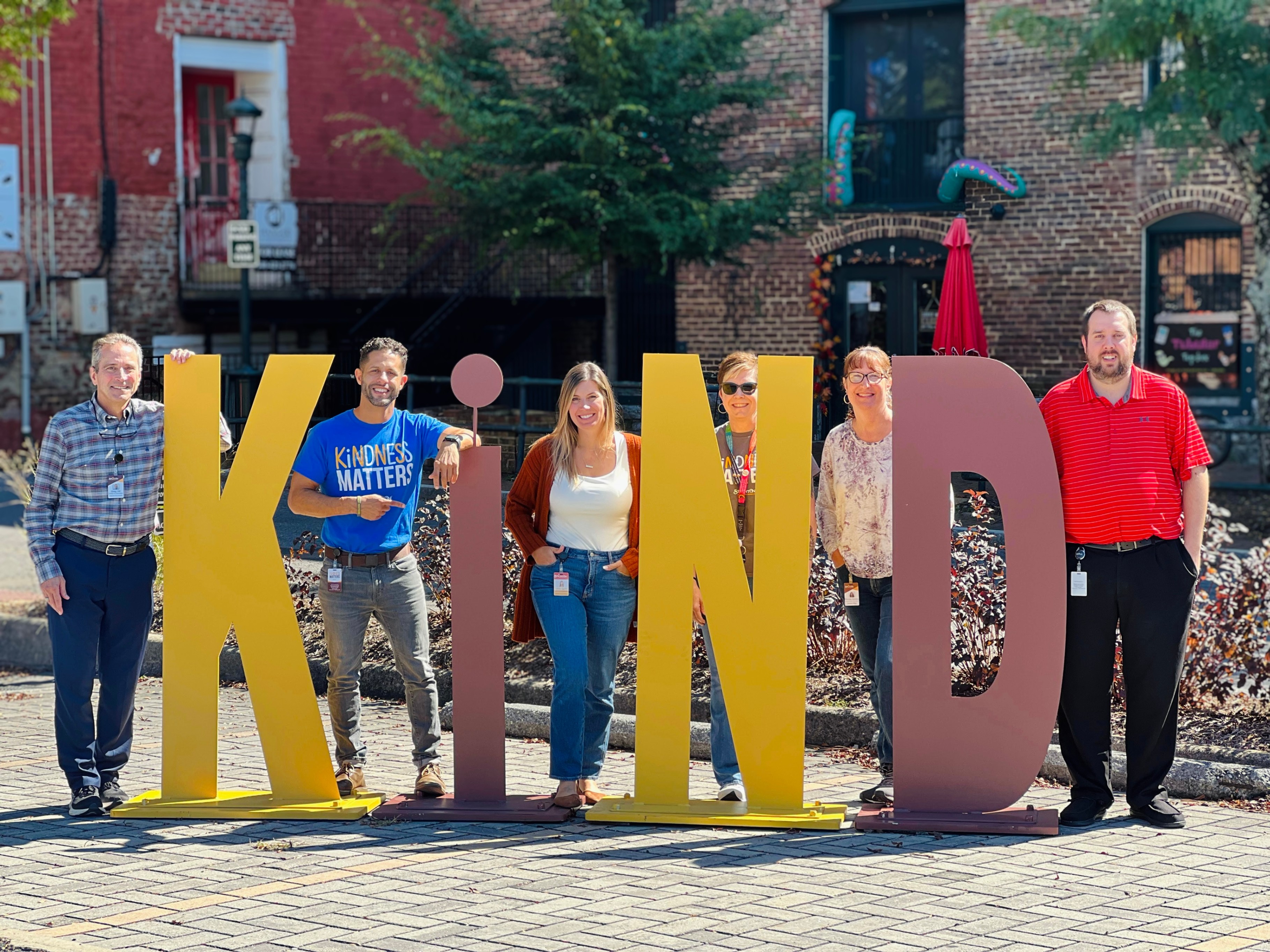 staff pose with the Kind sign